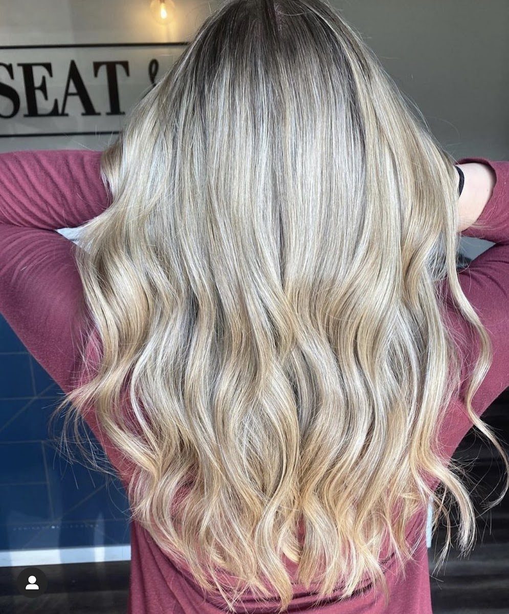 Long blonde balayage with a soft shadow root and loose waves